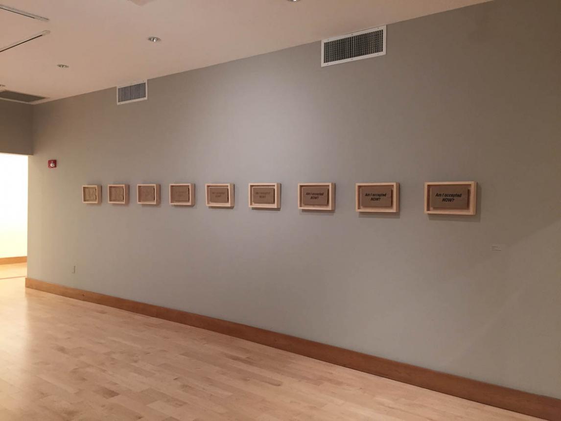 Gallery room view of 9 small framed prints in a neat row