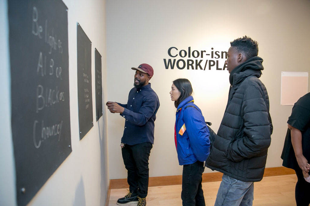Three people looking at three different wall pieces